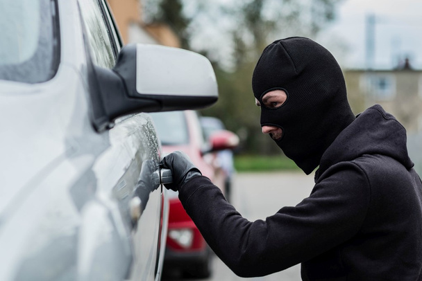 Car thief pulls the handle of a car. - Valokuva, kuva