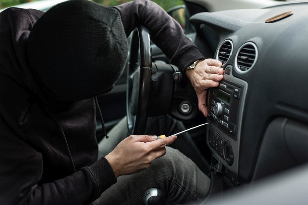 車泥棒の頭の車のラジオを盗むためにしようとしています。  - 写真・画像
