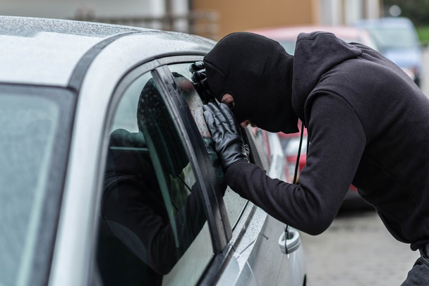 Car thief looking through car window  - Zdjęcie, obraz