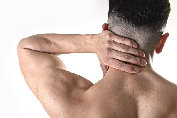 молодой мускулистый спортсмен с больной шеей массирует шейную область, страдая от боли в теле
 - Фото, изображение