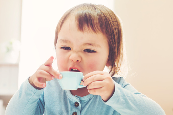 Happy toddler girl drinking from a teacup - Fotoğraf, Görsel