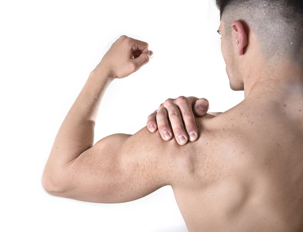 young muscular sport man holding sore shoulder in pain touching massaging in workout stress - Fotó, kép