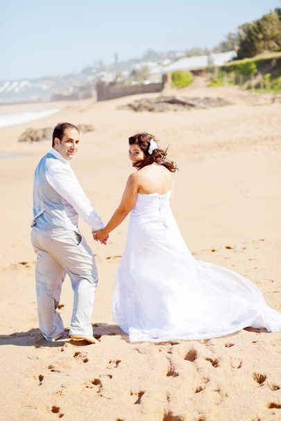 Bride and groom walking on beach - Φωτογραφία, εικόνα