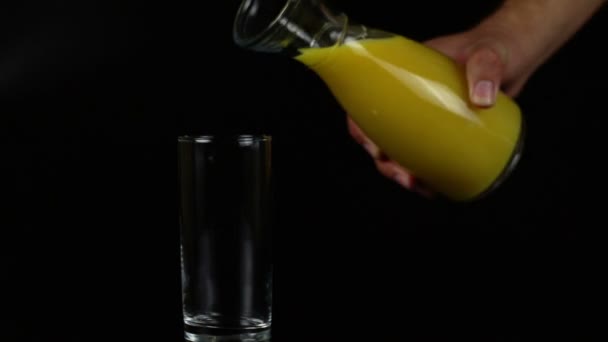 Mann gießt Orangensaft in ein Glas auf schwarzem Hintergrund - Filmmaterial, Video