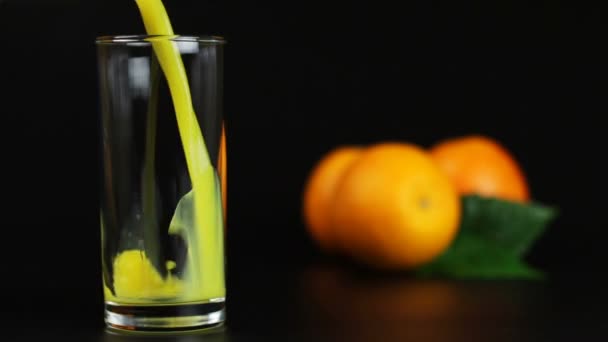 Homem derramando suco de laranja em um copo em um fundo preto
 - Filmagem, Vídeo