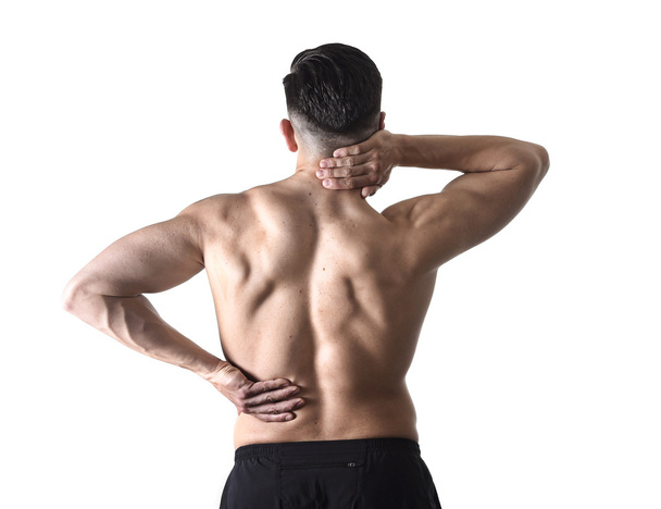 back view of young man with muscular body holding his neck and low back suffering spinal pain - Fotografie, Obrázek