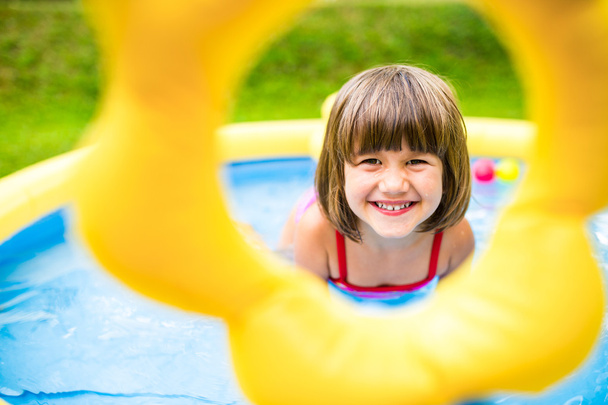 Mała dziewczynka zabawy w ogrodzie basen. - Zdjęcie, obraz