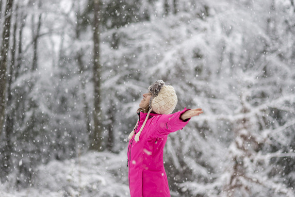 Szczęśliwa młoda kobieta stoi w śniegu blizzard, z jej ramiona rozłożone - Zdjęcie, obraz