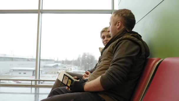 Casal esperando no terminal do aeroporto com bilhetes
 - Filmagem, Vídeo