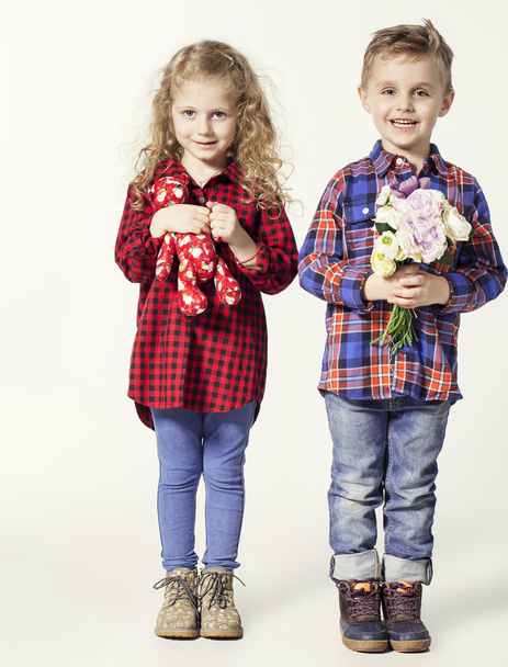 Funny lovely children.  fashionable little boy and girl in  jeans and plaid shirts. little boy gives flowers to girl. stylish kids in casual shoes. fashion children - Foto, imagen