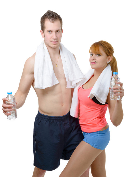Man and woman at gym in fitness attire holding water bottles  - Fotó, kép