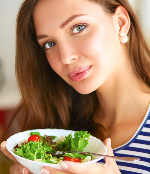 Mladá žena jíst salát a drží míchaný salát - Fotografie, Obrázek