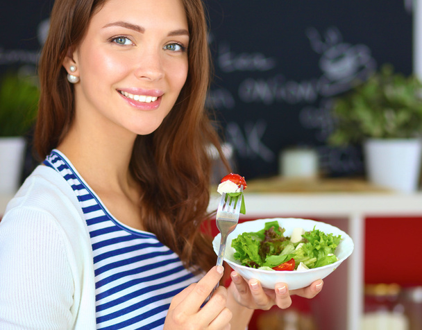 Mujer joven comiendo ensalada y sosteniendo una ensalada mixta
 - Foto, Imagen