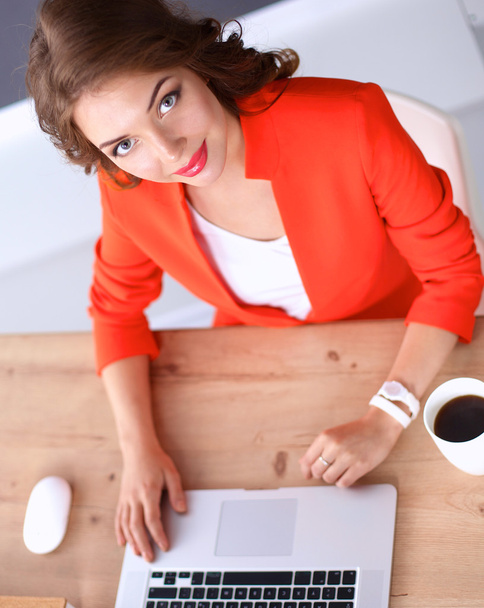 Attraktive Frau sitzt im Büro am Schreibtisch und arbeitet mit Laptop - Foto, Bild