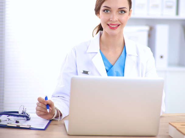 Ärztin sitzt auf dem Schreibtisch und arbeitet am Laptop - Foto, Bild