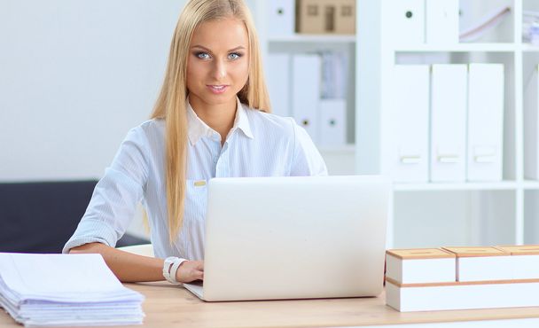 オフィスのノートパソコンと机の上に座っている魅力的なビジネスマンの女性 - 写真・画像