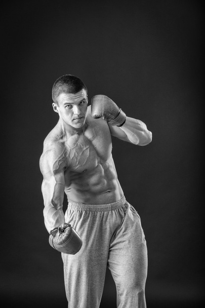 L'uomo con i guanti da boxe. Giovane pugile Boxer su sfondo nero. Boxe pronto a combattere. Boxe, allenamento, muscoli, forza, potenza: il concetto di allenamento della forza e pugilato
 - Foto, immagini