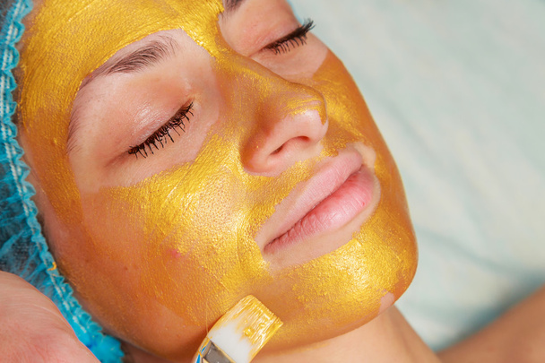 Applicazione di maschere dorate sul volto del modello. Procedure cosmetiche
 - Foto, immagini
