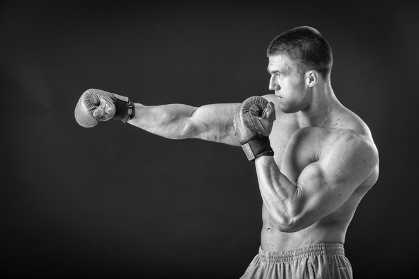L'uomo con i guanti da boxe. Giovane pugile Boxer su sfondo nero. Boxe pronto a combattere. Boxe, allenamento, muscoli, forza, potenza: il concetto di allenamento della forza e pugilato
 - Foto, immagini