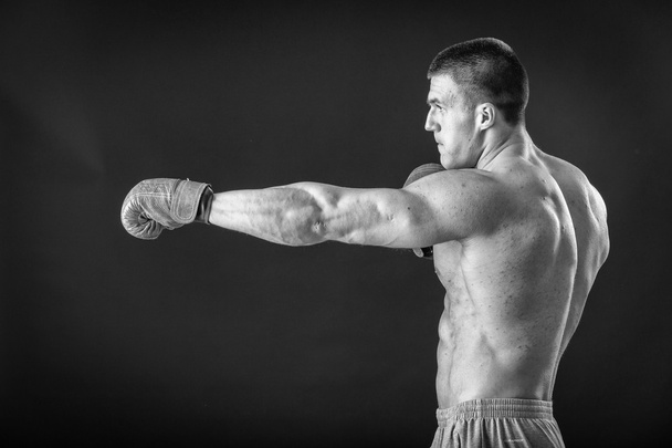 De man in bokshandschoenen. Jonge bokser vechter op zwarte achtergrond. Boksen man klaar om te vechten. Boksen, training, spiermassa, kracht, macht - het concept van krachttraining en boksen - Foto, afbeelding