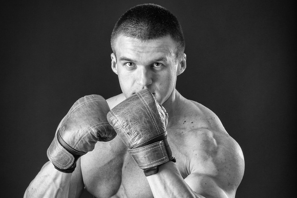 Az ember a boksz-kesztyűket. Young Boxer harcos felett fekete háttér. Boksz a harcra kész férfi. Boksz, edzés, izom, erő, erő - erő képzés és a boksz fogalma - Fotó, kép