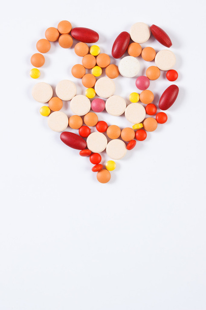 Heart shaped medical pills and capsules on white background, health care concept, copy space for text - 写真・画像
