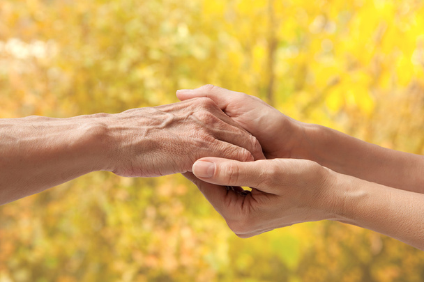 Τα χέρια της μια ηλικιωμένη ανώτερος κρατώντας το χέρι μιας γυναίκας - Φωτογραφία, εικόνα