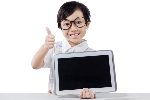 Child shows tablet and thumb up in studio - Φωτογραφία, εικόνα