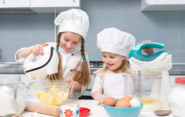 two little girls in chef uniform with ingredients on table - Fotó, kép