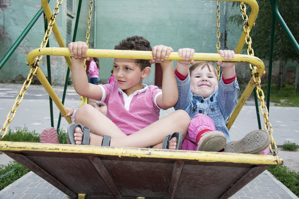 En été, les enfants au terrain de jeux sur une balançoire
. - Photo, image