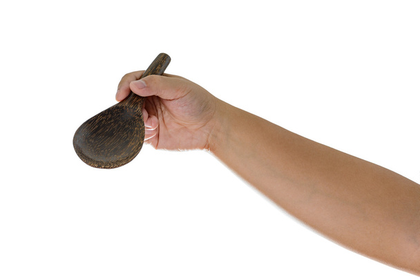 Рука держит деревянную кухонную ложку для перемешивания и дегустации foo
 - Фото, изображение