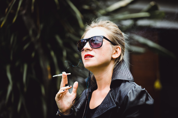 Beautiful woman smokes a cigarette. - Фото, изображение
