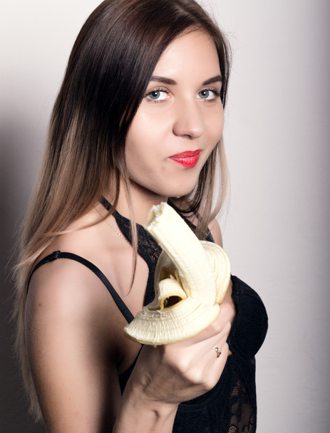 Young amazed woman in lacy lingerie holding a banana, she is going to eat a banana. woman offers to eat banana - Photo, Image