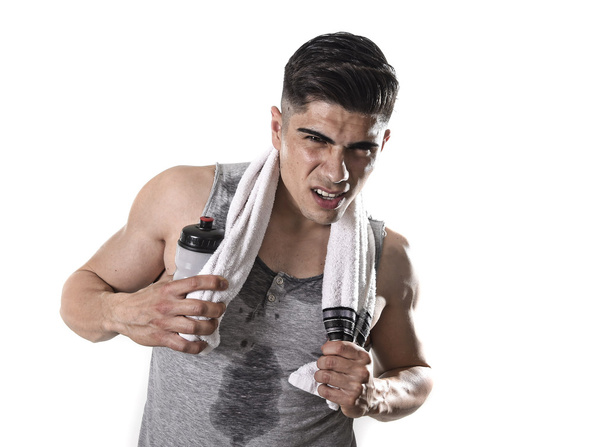 young tired sport man with athletic fit body holding towel and water bottle in exhausted face expression - 写真・画像