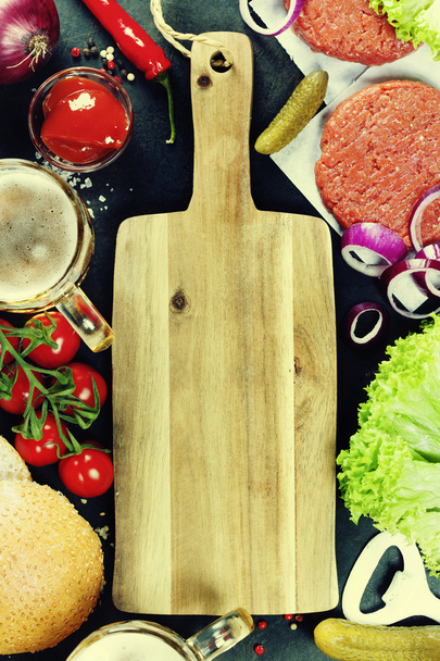 Huisgemaakte Hamburger ingrediënten, bier en lege snijplank - Foto, afbeelding