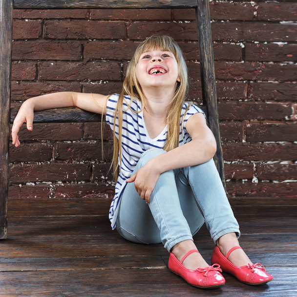 Tyttö 6-vuotias farkut ja liivi istuu
 - Valokuva, kuva