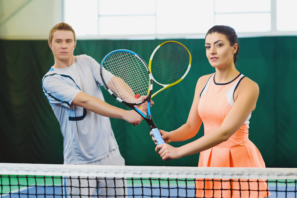 Mixed Doubles player hitting tennis ball, partner standing near net - Foto, Imagen