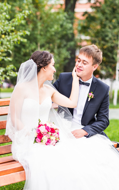 Abbracci di coppia, la sposa che tiene un mazzo di fiori, lo sposo che la abbraccia all'aperto
 - Foto, immagini