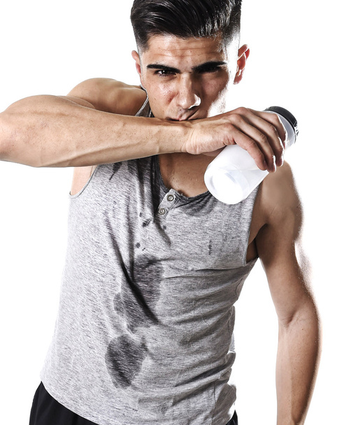nuori urheilullinen mies janoinen tilalla pullo vettä hikinen kasvot ja märkä singlet
 - Valokuva, kuva