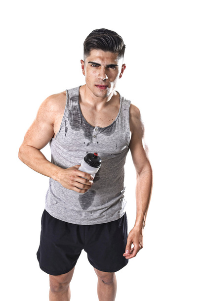 young athletic sport man thirsty holding bottle of water with sweaty face and wet singlet - Фото, зображення