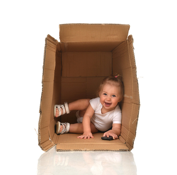 Happy little child baby girl hiding in a cardboard box having fu - Foto, Imagen