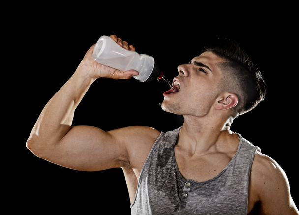 junger Sportler durstig Trinkwasser mit Flasche, die Flüssigkeit ins verschwitzte Gesicht schüttet  - Foto, Bild