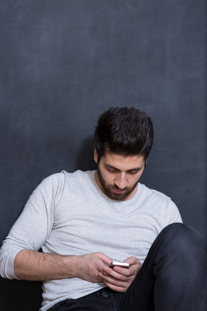 Casually handsome. Handsome young arabic man holding cell phone  - Фото, изображение