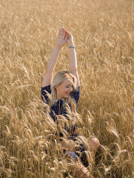 Attractive blonde walking and posing on a rye field in summer da - Photo, Image