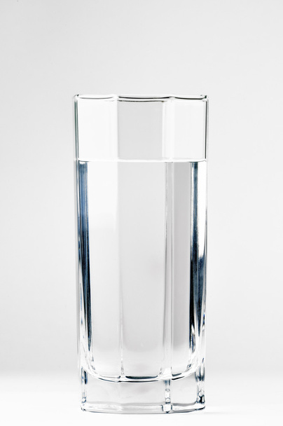 Con un vaso de agua sobre un fondo blanco
 - Foto, imagen