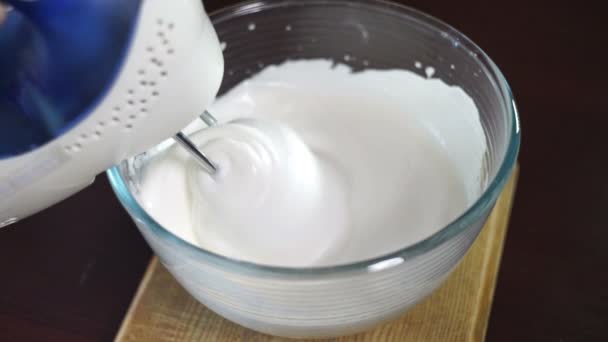 Whipping cream with electric mixer. Add yolk while mixing cream in glass bowl - Footage, Video