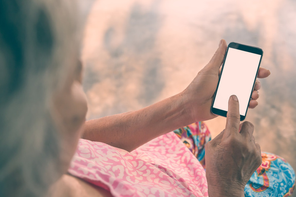 Mujer anciana usando un teléfono inteligente. Filtro Vintage
. - Foto, imagen
