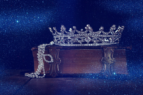low key image of decorative crown on old book. vintage filtered. - Photo, image