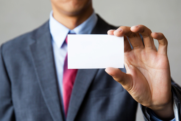Young man in business suit holding white blank business card.  - Fotoğraf, Görsel