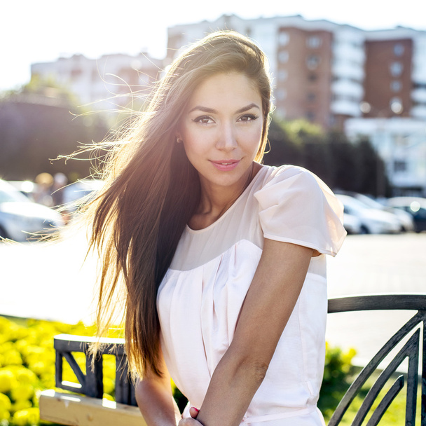 Beautiful girl sitting on a bench, sunny summer day, fashion style urban life - Foto, Imagen
